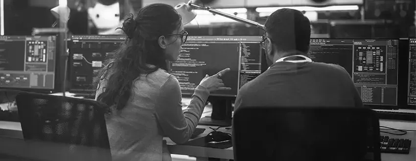 2 people talking in front of monitors